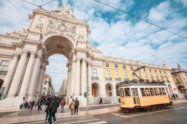 Lizbon, Portekiz. 4 Ocak 2019: Rua Augusta Zafer Kemeri Portekiz 'in Lizbon şehrinin tarihi merkezinde. Sokakta yürüyen insanlar. Bulutlu mavi gökyüzü. Şehir taşımacılığı için tramvay.