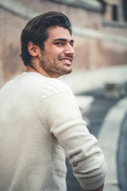 Dışarıda gülen yakışıklı bir delikanlı. Şık saç stili, sakallı. Şehirdeki caddede. Arkadan..