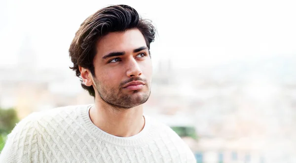 Güzel model İtalyan erkeği. Dışarıda yalnız başına yakışıklı genç bir adam, olumlu ve tatmin edici bir tavırla bir tarafa bakıyor. Herhangi bir özelleştirmenin eklenmesi için kenarda çok yer.