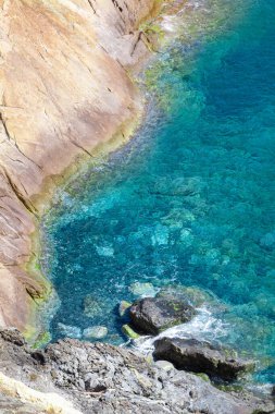 Kıyı şeridi, yamaçta kayalar ve yamaçta kayalar. İtalya 'nın Toskana bölgesindeki Elba adasının mavi denizi. Kristal berrak deniz. Akdeniz