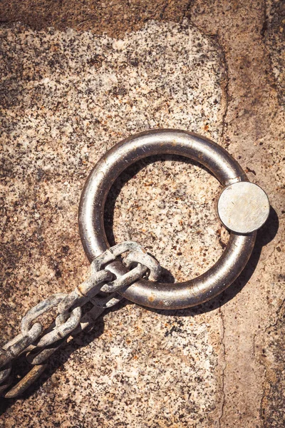 Steel ring and mooring lines in a seaport. Rusty iron chain on the ground.