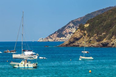 Elba Adası, İtalya. 26 Haziran 2016: Mavi deniz, bazı tekneler ve deniz taşlı dağlar. İtalya 'nın Toskana bölgesindeki Elba Adası kıyıları. Yaz mevsiminde turistler arasında çok popüler bir yer..