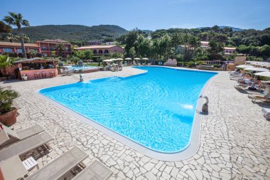 Açık yüzme havuzu. Yüzme havuzu ve havuzu olan bir kaplıca. Tepeler ve uzaktaki yeşil ağaçlar. Yeri: Procchio, Elba Adası. İtalya.