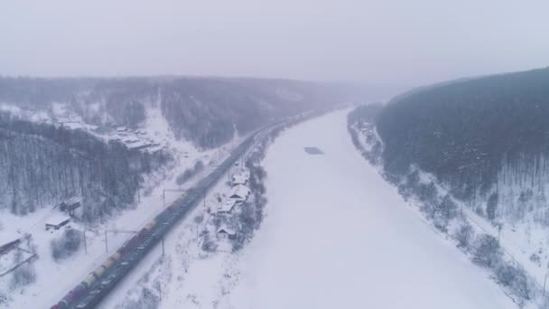 Два вантажних поїзди і річка Фрозен. Зимовий пейзаж. Повітряний вид — стокове відео