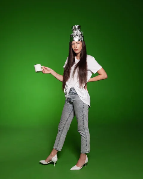Woman wearing tinfoil hat and holding a cup — 스톡 사진