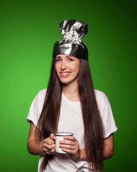 Mujer con sombrero de papel de aluminio y sosteniendo una taza Imagen de archivo