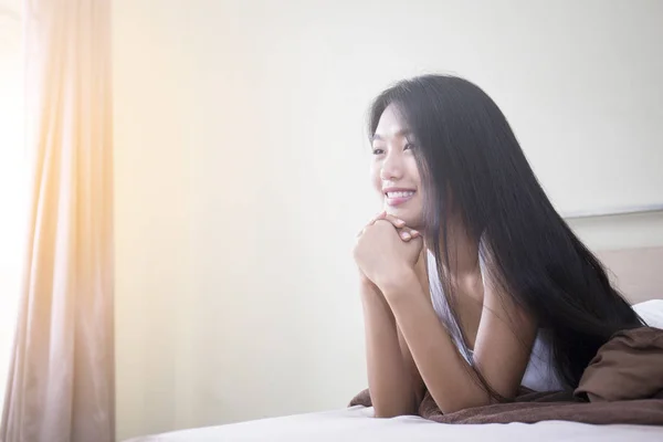 美丽年轻的亚裔女子，和迷人的微笑，躺在床上 — 图库照片