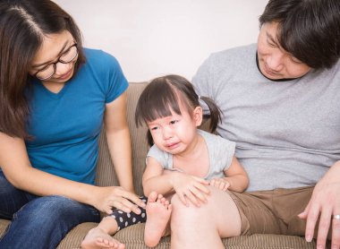 Asyalı kız ebeveynler arasinda otururken ağlıyor 