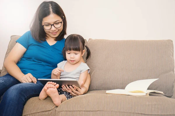 Anne ve kızı tablet bilgisayar kanepenin üzerinde seyir
