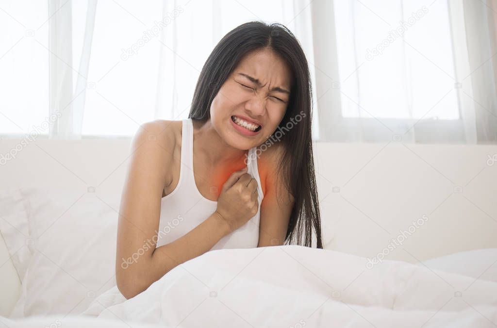 Asian woman having heart attack while in bed 
