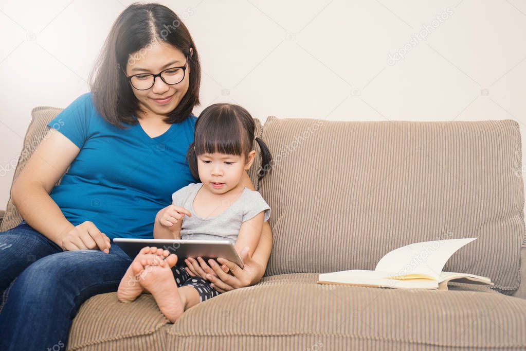 Mother and daughter looking at tablet computer on sofa