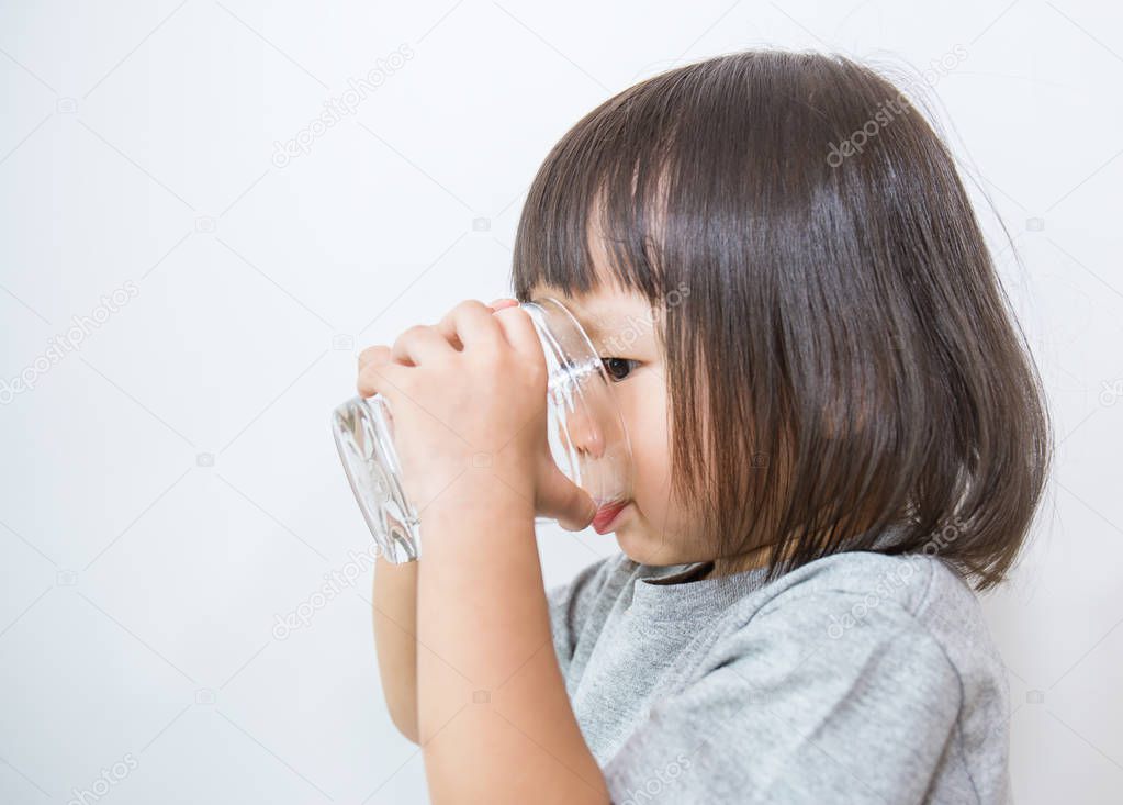 Portrait of young little girl drinking a glass of water