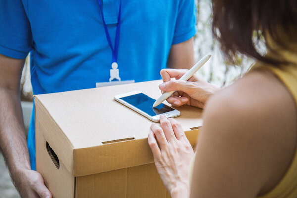 Женщина прикрепляет подпись знака после принятия получить доставку коробки от курьера, получить и доставить концепцию
 