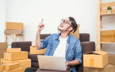 office evde bilgisayar yazmaya kutuları, yakınındaki kanepede oturan, parmağını serbest Asya adam