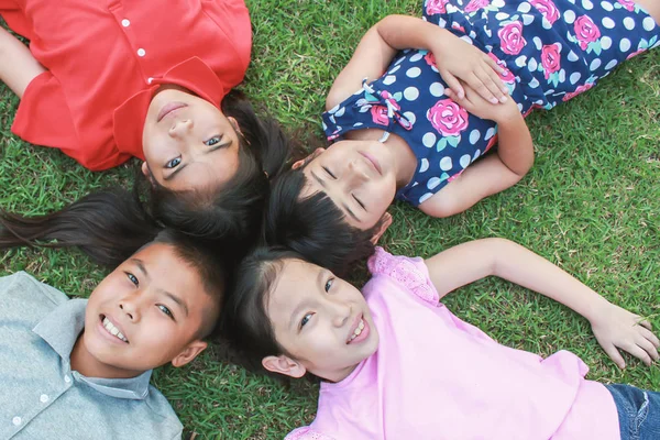 Cuatro Niños Acostados Sobre Hierba Verde Mirando Hacia Arriba Parque — Foto de Stock