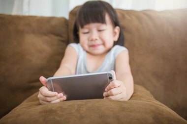 Asyalı kız evde kanepede oturan smartphone kullanarak