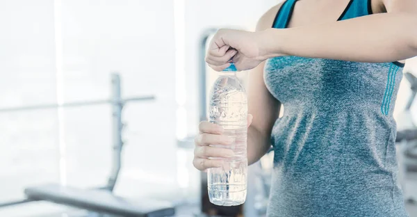 Asian young woman openning bottle after exercises at sport club gym