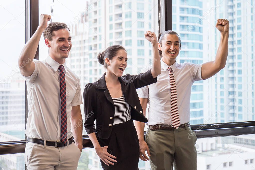 Group of employees with hands up in fists and having fun at business meeting