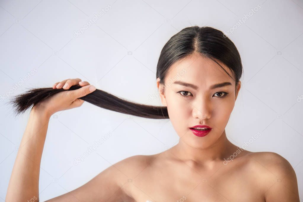 portrait of beauty young asian woman with hand pulling long black hair posing at camera isolated on white background