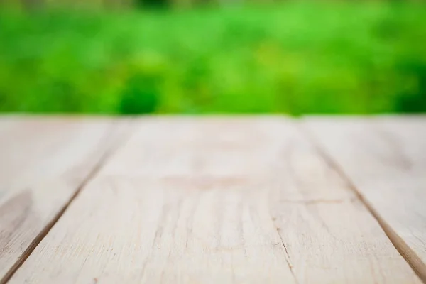 Mesa de madeira em um fundo de árvores verdes brilhantes no desfoque — Fotografia de Stock