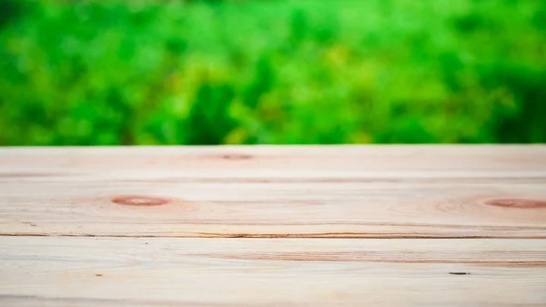 Drewniany stół na tle jasnej zieleni w rozmycie — Zdjęcie stockowe