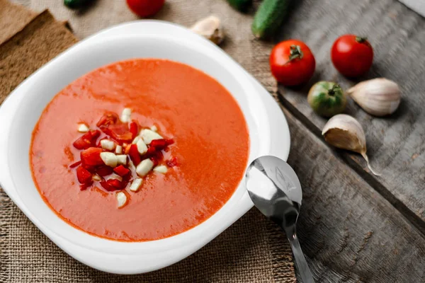 Ahşap Komiteler arka plan üzerine bir havlu üzerinde beyaz kase kaşık gaspaço domates çorbası