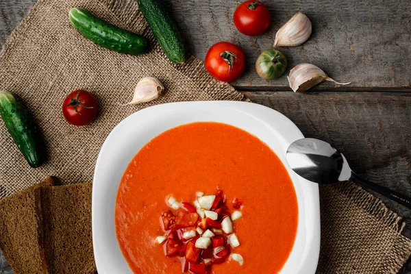 Ahşap Komiteler arka plan üzerine bir havlu üzerinde beyaz kase kaşık gaspaço domates çorbası
