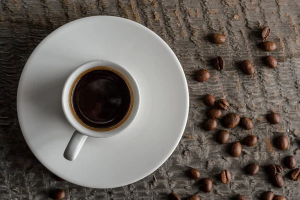 Top kahve fincanı ve kahve çekirdekleri ahşap masa arka plan üzerinde görünümü