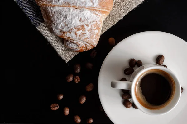 Taze kruvasan ve kahve siyah arka plan üzerine