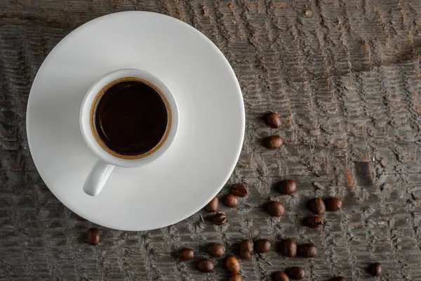 Top kahve fincanı ve kahve çekirdekleri ahşap masa arka plan üzerinde görünümü