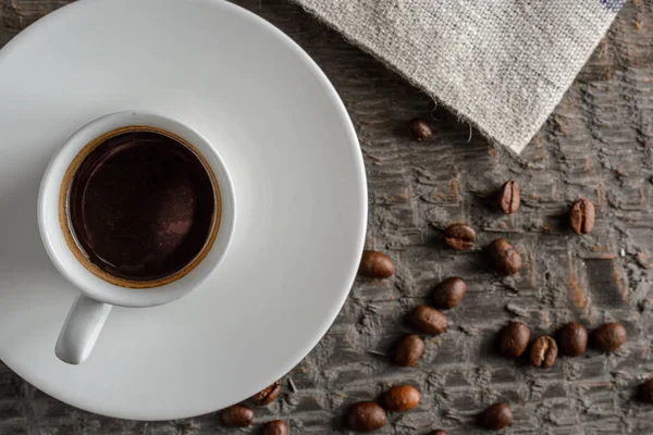 Top kahve fincanı ve kahve çekirdekleri ahşap masa arka plan üzerinde görünümü