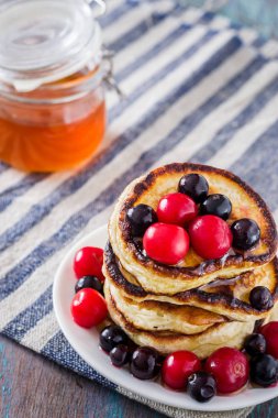 Beyaz tabak dolusu krep çilek ve ballı ahşap arka plan üzerinde