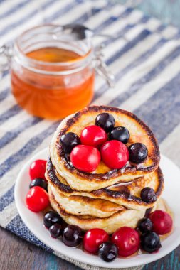 Beyaz tabak dolusu krep çilek ve ballı ahşap arka plan üzerinde