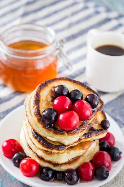 Beyaz tabak dolusu krep çilek ve ballı ahşap arka plan üzerinde