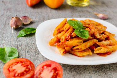 Domates sosu ve ahşap arka plan üzerinde fesleğen ile Penne