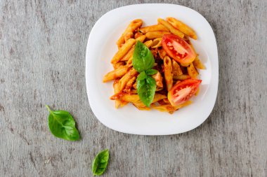 Domates sosu ve ahşap arka plan, üstten görünüm üzerinde fesleğen ile Penne.