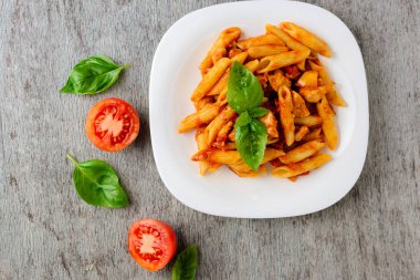 Domates sosu ve ahşap arka plan, üstten görünüm üzerinde fesleğen ile Penne.