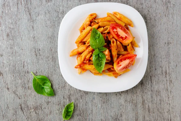 Domates sosu ve ahşap arka plan, üstten görünüm üzerinde fesleğen ile Penne.