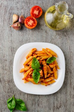 Domates sosu ve ahşap arka plan, üstten görünüm üzerinde fesleğen ile Penne.