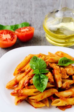 Domates sosu ve ahşap arka plan üzerinde fesleğen ile Penne