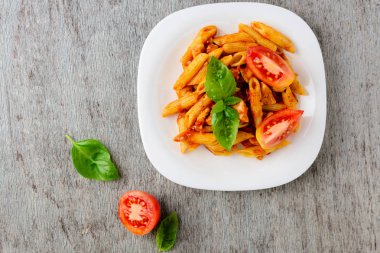 Domates sosu ve ahşap arka plan, üstten görünüm üzerinde fesleğen ile Penne.