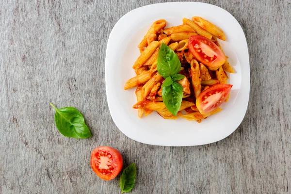 Domates sosu ve ahşap arka plan, üstten görünüm üzerinde fesleğen ile Penne.