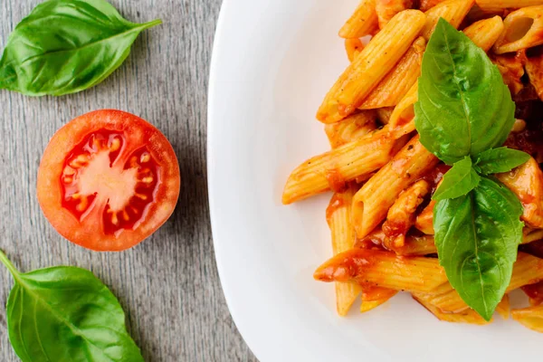 Domates sosu ve ahşap arka plan, üstten görünüm üzerinde fesleğen ile Penne.