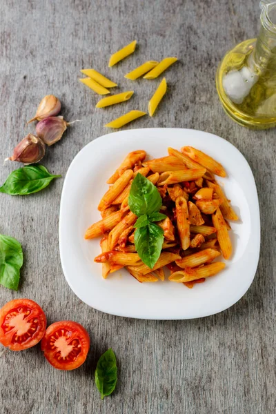 Domates sosu ve ahşap arka plan, üstten görünüm üzerinde fesleğen ile Penne.