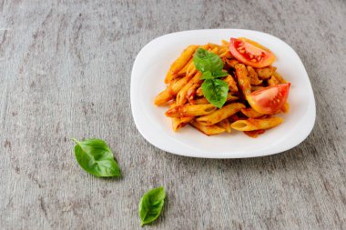 Domates sosu ve ahşap arka plan üzerinde fesleğen ile Penne