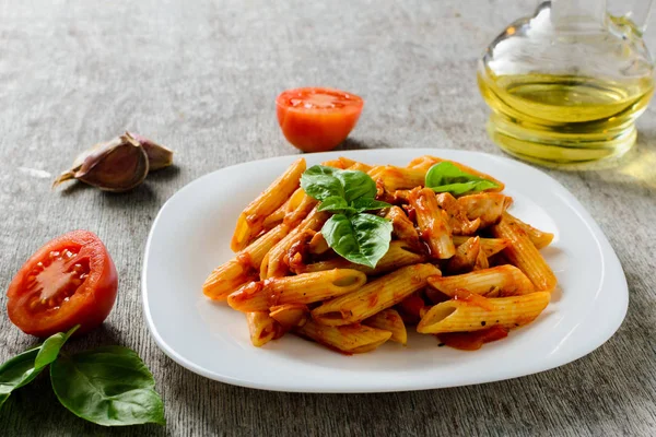 Domates sosu ve ahşap arka plan üzerinde fesleğen ile Penne