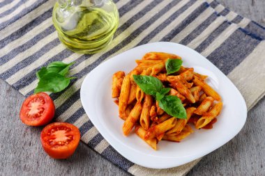 Domates sosu ve ahşap arka plan üzerinde fesleğen ile Penne