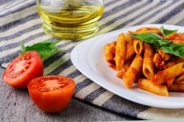 Domates sosu ve ahşap arka plan üzerinde fesleğen ile Penne