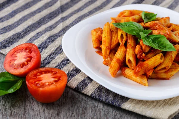 Penne with tomato sauce and basil on a background of striped cloth — Stock Photo, Image