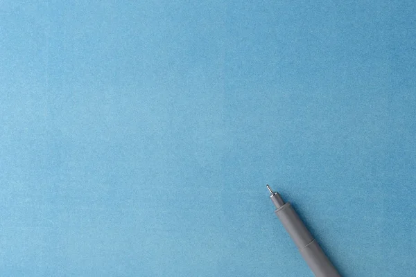 Pluma gris sobre una hoja de papel en blanco azul — Foto de Stock